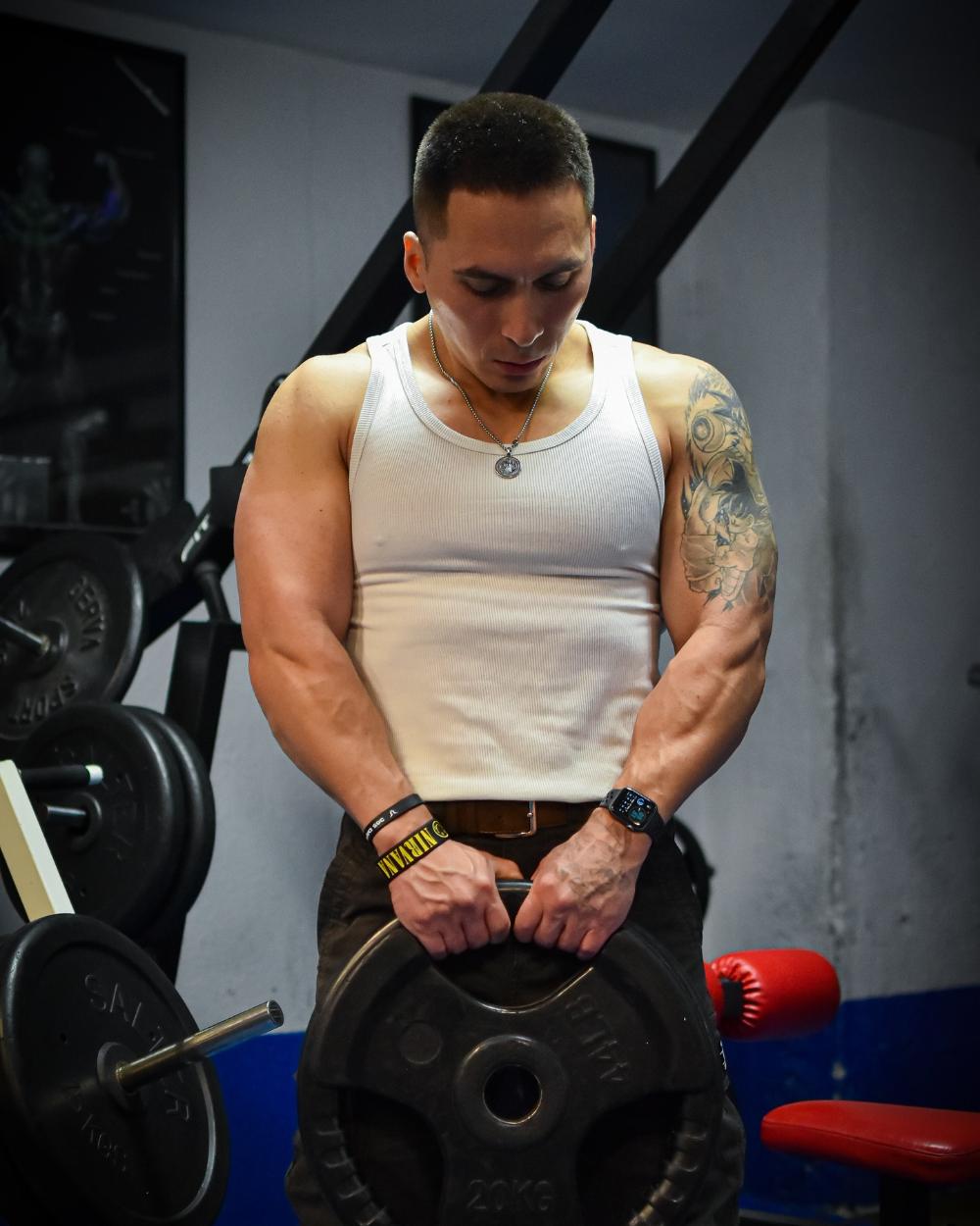 Eddie Torres sujetando un disco de 20 kg en el gimnasio